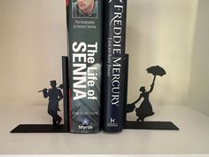 two books are sitting on top of each other in front of a bookend with an image of a man holding an umbrella