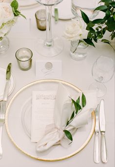 the table is set with white flowers and silverware