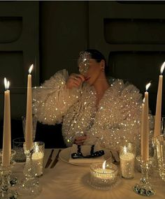 a woman sitting at a table with candles and wine glasses