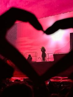 a person standing on top of a stage in front of a heart shaped object at night