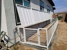 a fenced in area next to a building with windows on the top and bottom