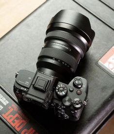 a black camera sitting on top of a table next to a pair of glasses and a book