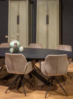 a dining room table with six chairs and two cupboards in the back wall behind it