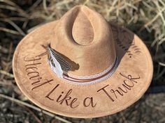 This Lainey Wilson - Heart Like a Truck - Wide Brimmed Cowgirl Hat is perfect for attending that upcoming Lainey concert... Or just displaying your fan crush!   Colors: Cream Sand (Light Tan) Cognac (Dark Tan) Each hat displays the "Heart Like a Truck" song title around the hat brim as well as a floral design.  Flowers are just my creative arrangements, but feel free to let me know if you have a specific flower that you would like me to include.  I've had requests for magnolias, roses, and sunfl Lainey Wilson Cowboy Hat, Lainey Wilson Hats, Cowgirl Concert, Hat Displays, Heart Like A Truck, Burned Hats, Concert Attire, Lainey Wilson, Wood Burn Designs