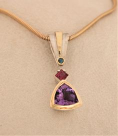 This vibrant sterling silver & 18K art deco inspired pendant/slide is set with a 5.5 ct. trillion checkerboard cut amethyst; a .80 ct. wine  colored square cut tourmaline; and a .11 ct. round bright teal colored tourmaline. Two of the three gemstones are bezel set in 18K, plus 18KY sheet was added to accent the large bail. It measures 1 3/4" X 5/8" and weighs 13 grams This piece comes with an 18" silk cord or rubber choker with  a sterling silver clasp & also looks great on either silver or gold Formal Trillion Cut Jewelry With Bezel Setting, Trillion Cut Jewelry With Bezel Setting For Formal Occasions, Formal Trillion Cut Multi-stone Jewelry, Elegant Trillion Cut Polished Jewelry, Silk Cord, Wine Colored, Art Deco Inspired, Teal Colors, Gold Chains