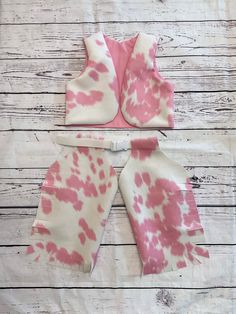 three pieces of pink and white tie - dyed clothing sitting on top of a wooden table