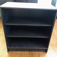 an empty black bookcase sitting on top of a hard wood floor