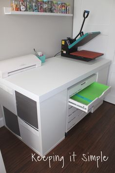 a white desk with drawers and a printer on it's shelf next to the wall