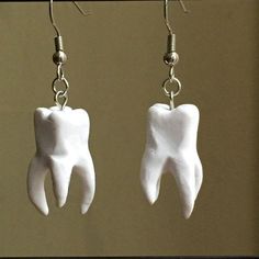 two tooth shaped earrings hanging from hooks