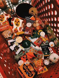 a red shopping cart filled with halloween treats and other items, including candies or candy