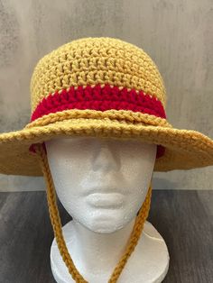 a white mannequin head wearing a yellow and red crochet sun hat