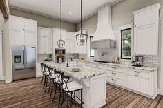 a large kitchen with white cabinets and marble counter tops, along with an island in the middle