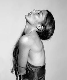 black and white photograph of woman in leather dress looking up at something on the wall