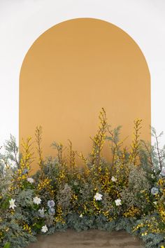 an arch in the wall is covered with flowers and plants on either side of it