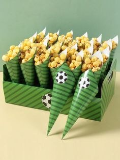 a green box filled with popcorn sitting on top of a table next to a soccer ball