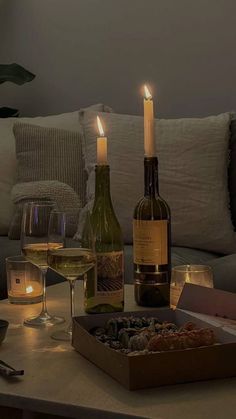 two bottles of wine are sitting on a coffee table with candles in front of them