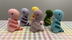 four crocheted toy animals sitting on top of a checkered tablecloth covered table