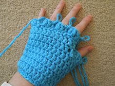 a hand with a blue crochet glove on it