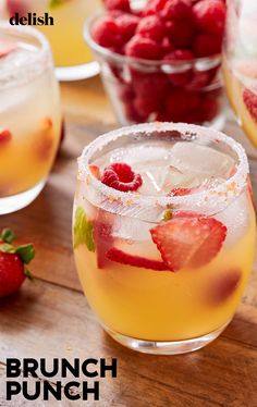 a close up of a drink on a table with strawberries in the glass and another behind it