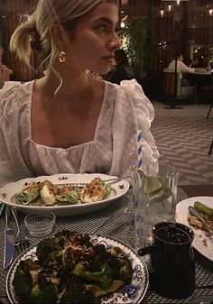 a woman sitting at a table with plates of food