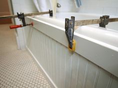 a bathroom with two hooks on the wall and a bathtub in the background,