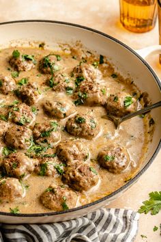 a skillet filled with meatballs and gravy next to a wooden spoon