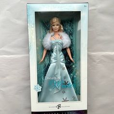 a barbie doll in a blue dress with white fur on it's head and snowflakes around her neck