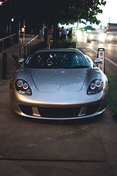 a silver sports car parked next to a parking meter on the side of a road