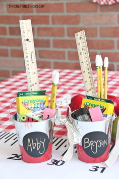 two buckets filled with school supplies on top of a table