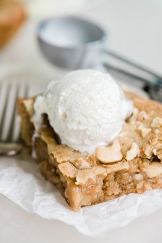 a piece of pie with ice cream on top sitting on wax paper next to a fork