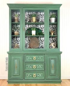 an old china cabinet painted green and decorated with gold trimmings on the doors