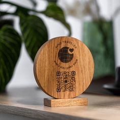 a wooden coaster sitting on top of a table next to a potted green plant