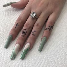 a woman's hand with green and white nail polishes on it, including an eye