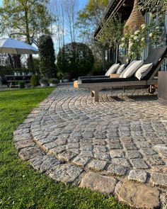 an outdoor patio with stone pavers and lounge chairs