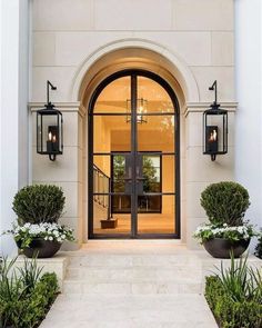 the entrance to a home with two large potted plants on either side of the door