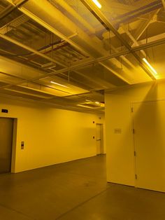 an empty parking garage with yellow walls and ceiling lights on either side of the door