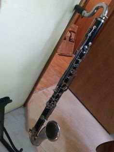 a silver musical instrument sitting on top of a hard wood floor next to a wall