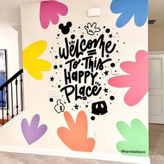 a welcome to this happy place sign painted on the side of a wall in a house