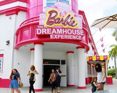 some people are walking around in front of a pink and white building with the words barbie's dreamhouse experience on it