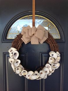 a wreath made out of seashells hangs on the front door's black door