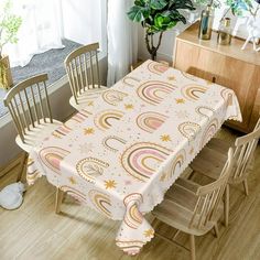 a dining room table covered with a white and pink paisley print cloth next to a potted plant