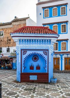 a blue and white building in the middle of a cobblestone street with buildings around it