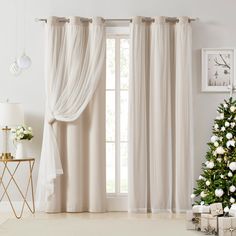 a living room with a christmas tree and white curtains