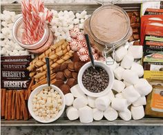 a tray filled with marshmallows, hot dogs and candy canes next to other snacks