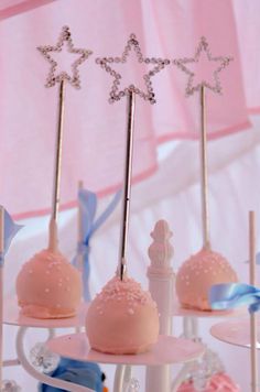 cake pops with stars on them are sitting on a stand in front of a pink curtain