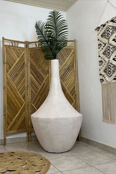 a large white vase sitting on top of a tiled floor next to a bamboo plant