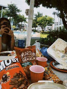 a woman taking a photo of food and drinks on a table with her cell phone