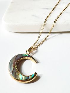 This Abalone shell necklace is  double sided and absolutely beautiful. Each necklace is unique with different iridescent hues and striations of color from the stunning abalone shell it was made from.  The abalone shell AKA  Mother-of-Pearl is a symbol of strength and healing.  Abalone is also thought to promote  soothing, calming, and peaceful energy. The abalone jewelry is an excellent gift. In some cultures it is believed to bring luck, peace, and prosperity to the person wearing it. The Moon Gold Bohemian Abalone Shell Necklace, Handmade Gold Jewelry With Abalone Shell, Gold Abalone Shell Pendant Jewelry, Gold Moon-shaped Wire Wrapped Jewelry, Gold Crescent Wire Wrapped Necklaces, Celestial Crescent Crystal Necklace For Gift, Gold Crescent Wire Wrapped Jewelry, Spiritual Crescent Jewelry With Adjustable Chain, Spiritual Crescent Wire Wrapped Necklaces