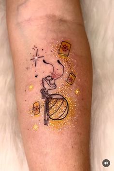 a person has a tattoo on their leg that looks like a mouse with gold glitters