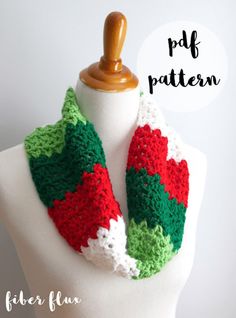 a white mannequin wearing a red, green and white crocheted scarf